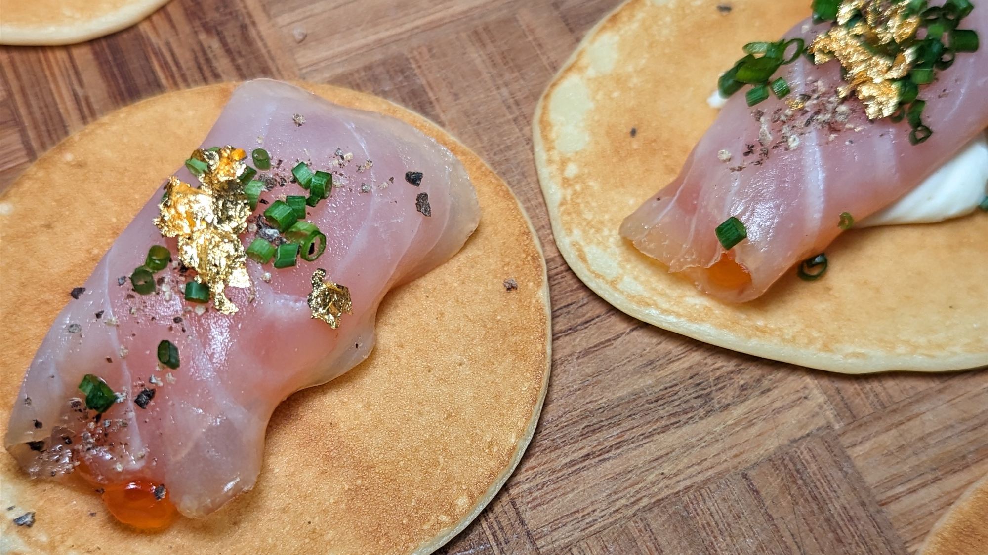 Cold-smoked amberjack with crème fraîche and salmon caviar on pancakes