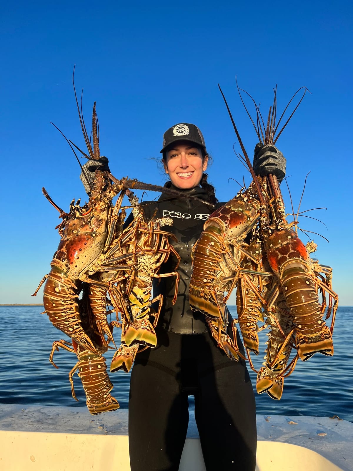Lauren Sarasua on the boat with two armfuls of spiny lobsters